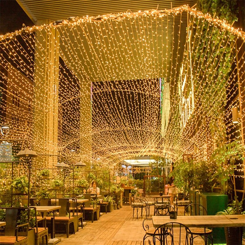 Golden string lights forming a canopy over an outdoor dining area
