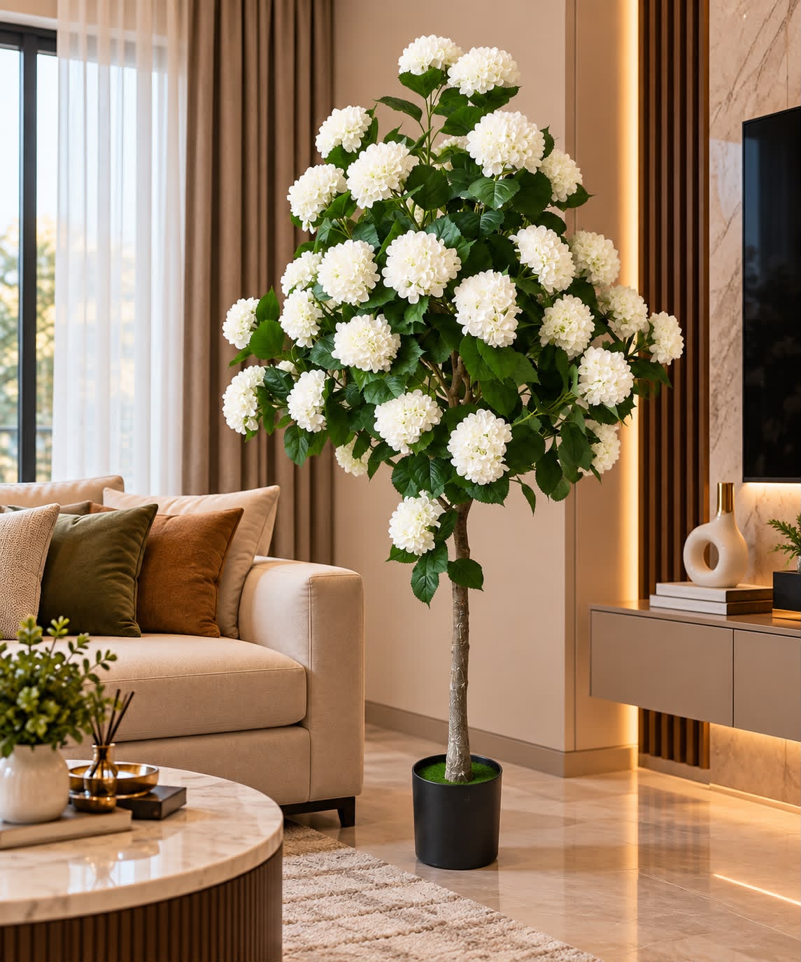 Artificial white hydrangea tree with abundant white flower clusters and lush green leaves in a black pot, displayed in a living room.