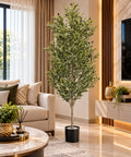Artificial olive tree with silvery-green foliage and dark olive fruits in a sleek black pot, displayed in a living room.