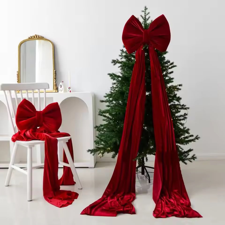 Oversized red bow with long draping ribbons styled on a Christmas tree beside a matching bow on a chair